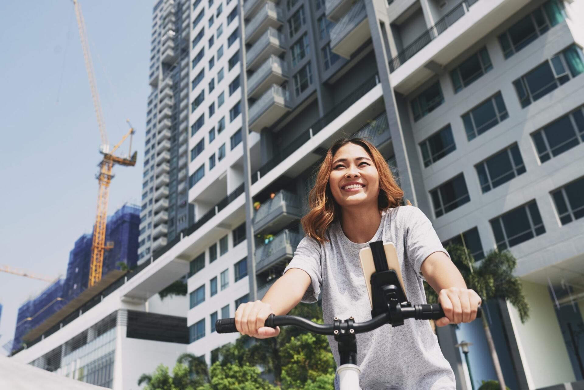 Moradora de bicicleta em frente a condomínio