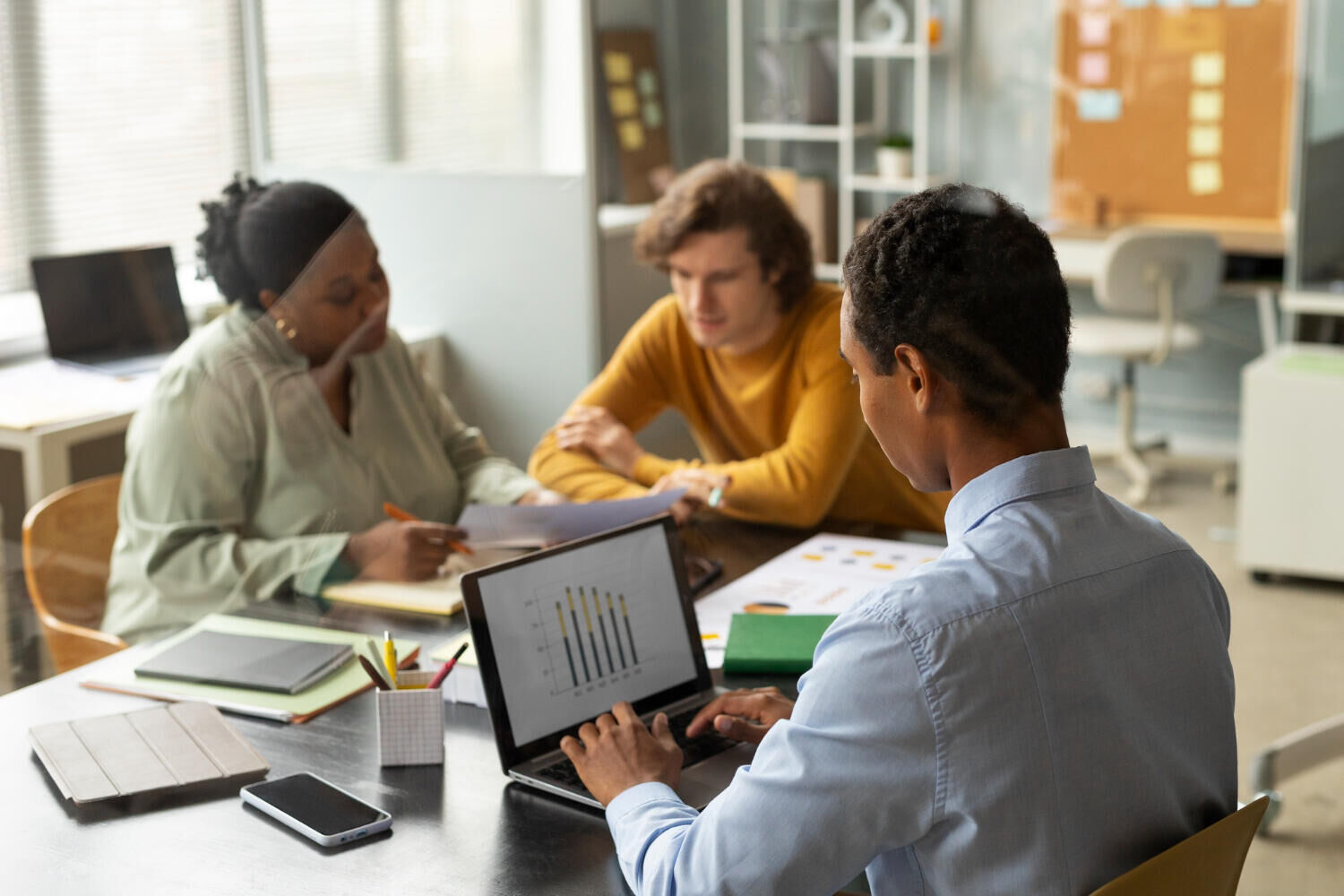 Equipe de escritório reunida analisando gráficos no notebook