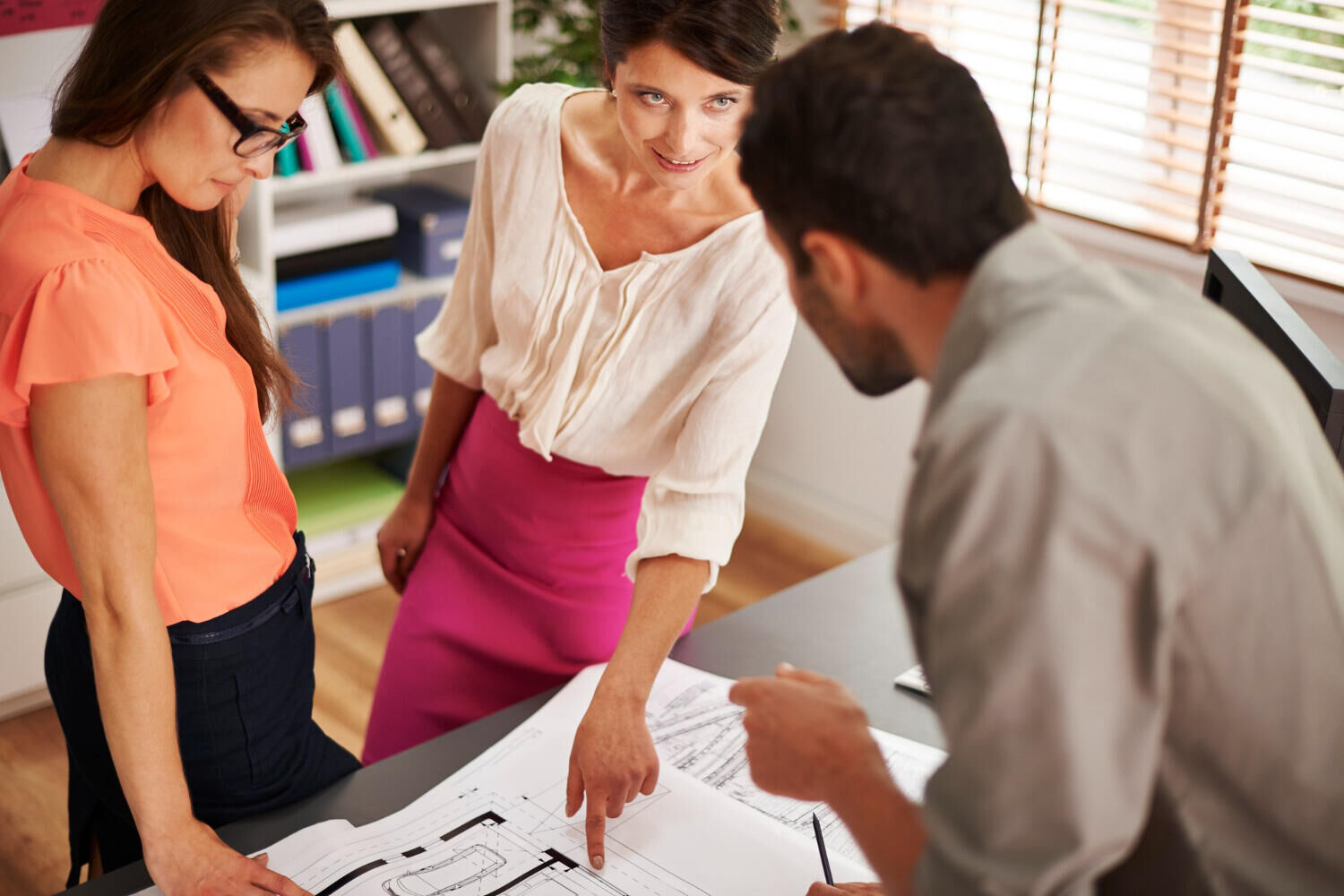 Equipe analisando plantas técnicas sobre a mesa do escritório