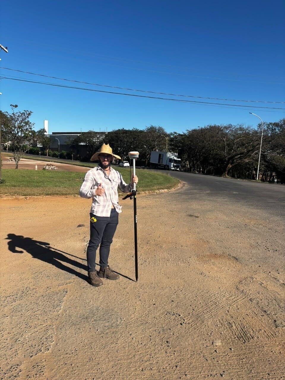Técnico da RC Geo com bastão GNSS em via de loteamento