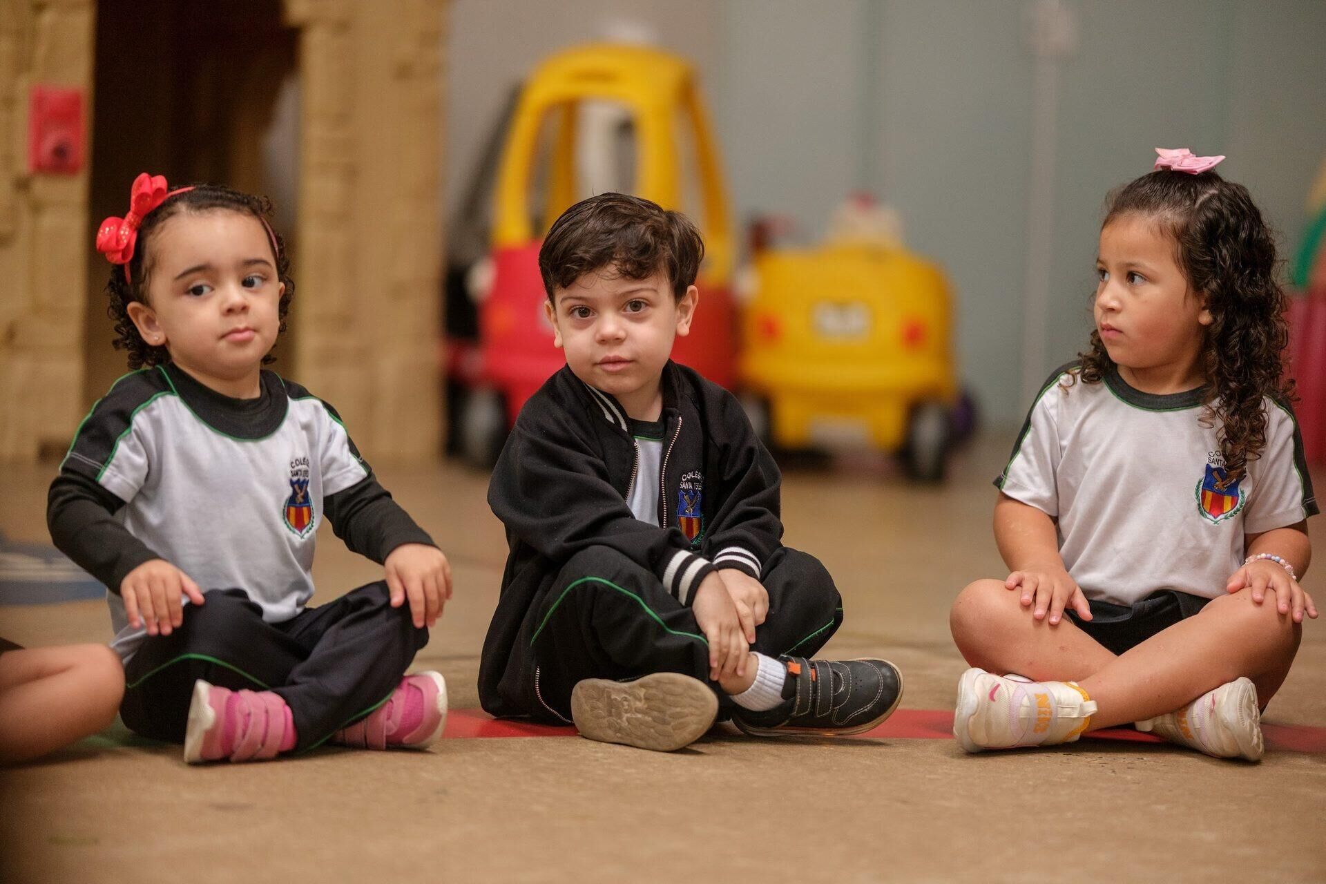 Crianças da Educação Infantil sentadas no chão da brinquedoteca