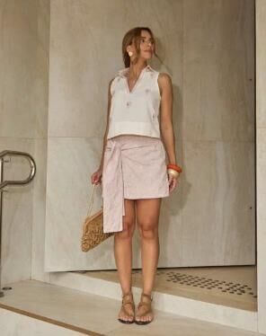 Modelo com blusa off-white sem manga e saia rosa clara da Fortina