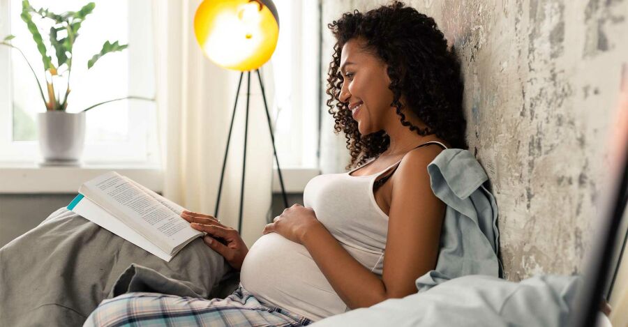 Mulher grávida lendo livros sobre 1ª maternidade | Reprodução: Internet