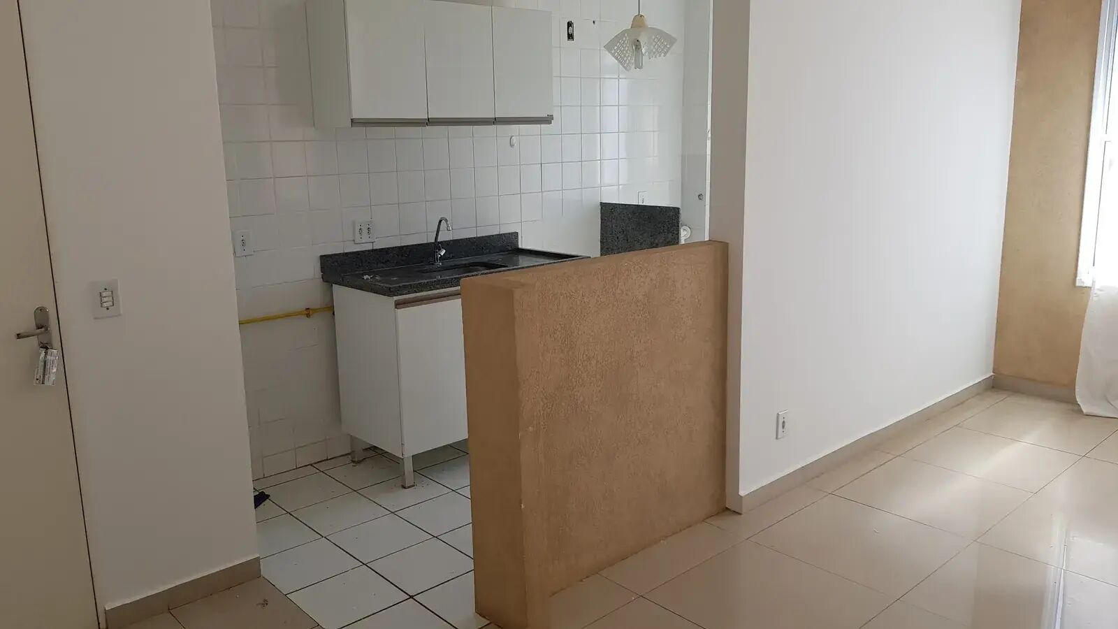 Cozinha integrada à sala por meia parede, com pia em granito e armários brancos