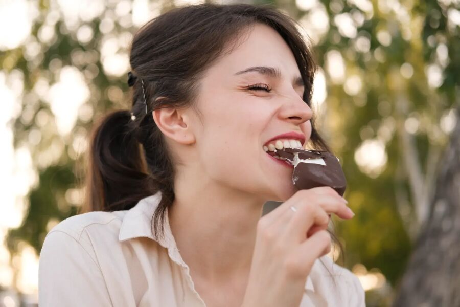 Imagem mulher-comendo-chocolate-ao-ar-livre-sorrindo